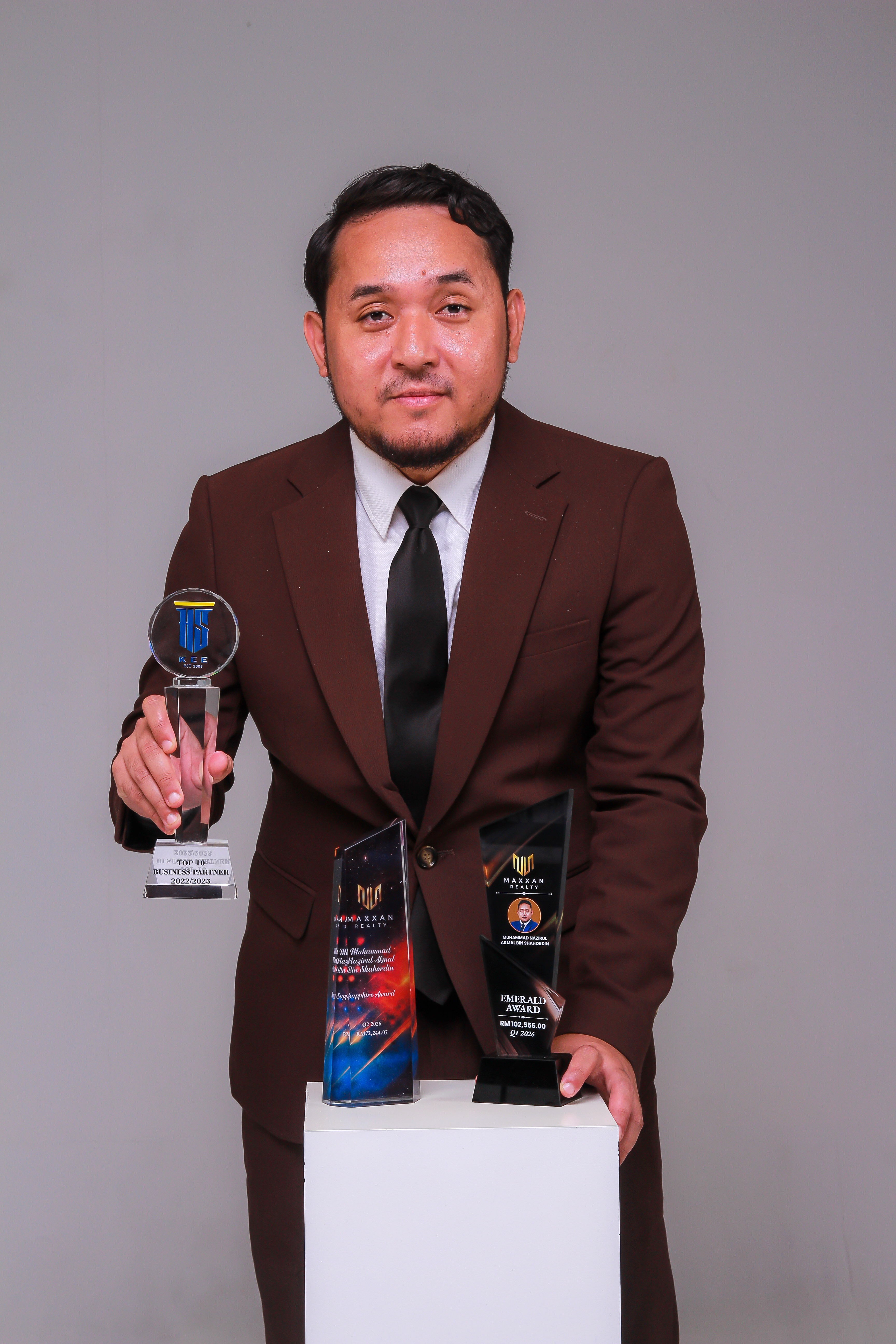 Nazirul Akmal, Group Sales Leader dan founder of Excellent Group, bersama trofi anugerah.